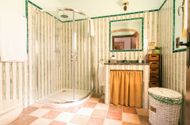 Baño con ducha acristalada, mueble de obra y azulejo de rayas