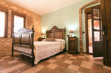 Dormitorio con cama de madera tallada y suelo de barro
