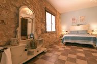Dormitorio con muro de piedra, tocador blanco con espejo y cama doble